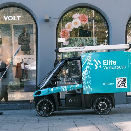 Vasking av vindu i bygate, med en elektrisk varesykkel parkert rett ved
