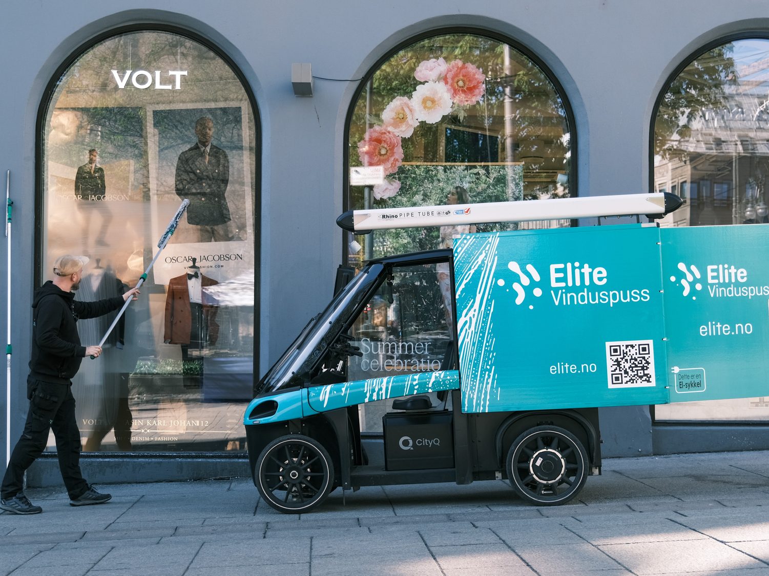 Vasking av vindu i bygate, med en elektrisk varesykkel parkert rett ved